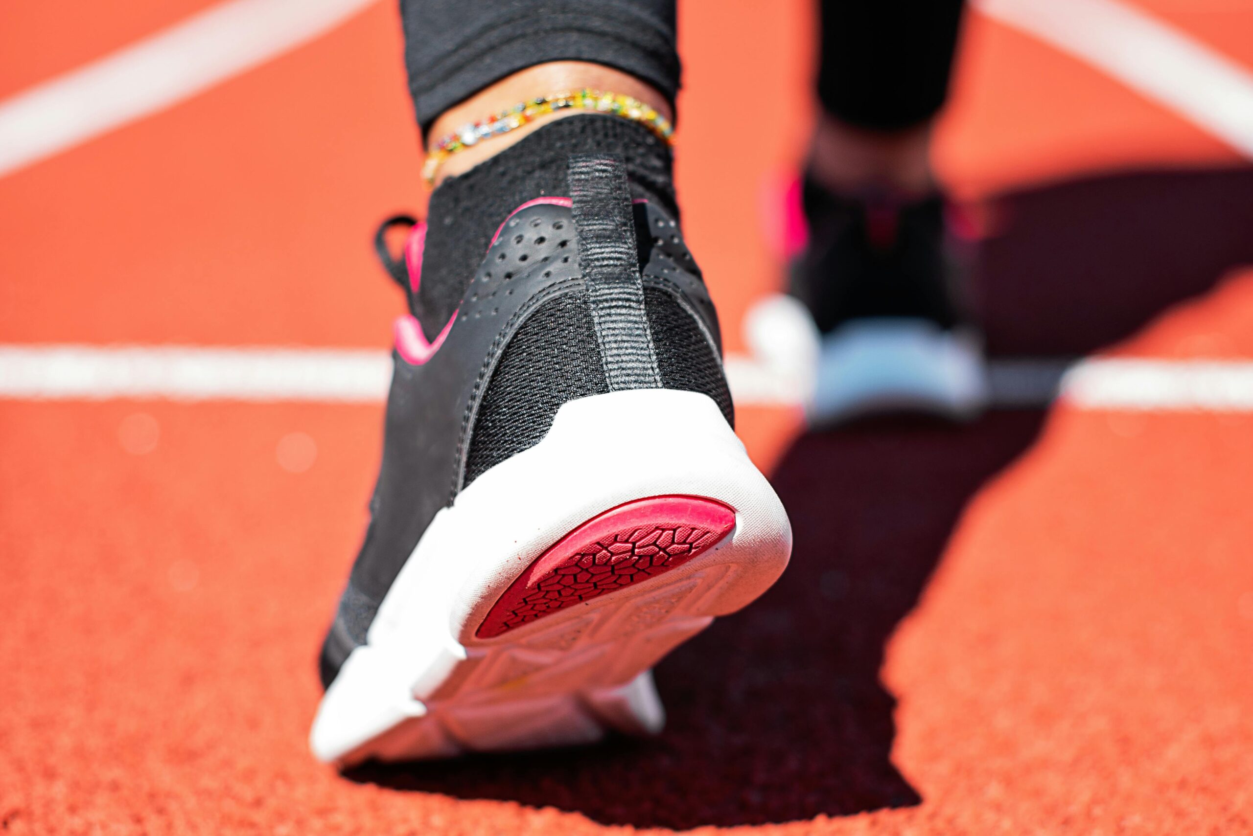 Close-up of a runner's foot with athletic sneaker on a vibrant track surface.